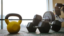 Photo of sport equipment in gym. Dumbbells on floor.