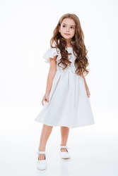 Full length of beautiful little girl in dress standing and posing over white background