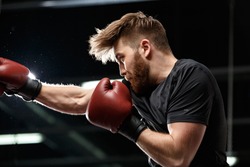 Image of concentrated handsome young strong sports man boxer make exercises in gym and looking aside.