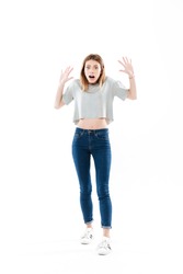 Full length portrait of a scared frightened girl standing and screaming isolated over white background