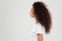 Pretty curly woman posing in profile over gray background