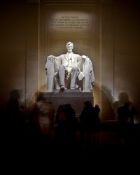 An image of the Lincoln Memorial taken at night.  Tourist move and gather around the monument.