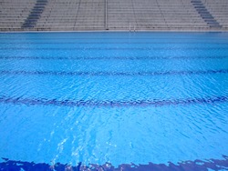 Trembling surface of an Olympic size swimming pool in empty sport arena