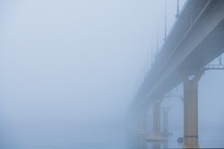 Autumn city landscape. Bridge over the river in heavy fog