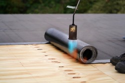 Bitumen roofing.  A with a gas burner and a roll of tar paper. Flat roof installation.