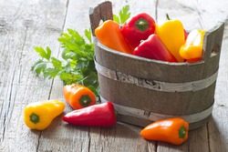 Sweet pepper in wooden pot on old boards background
