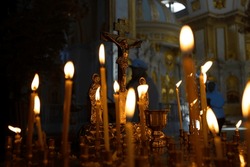 Concept of Christian religion. Cross with crucifix in focus, lit wax candles, an Orthodox church, memorial service, funeral service, prayers for salvation of soul.