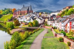 Saarburg, Germany. Idyllic city on Saar River with St. Laurentius church, beautiful autumn sunlight.