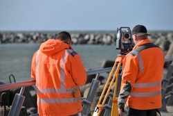 Surveyor workers with geodesy equipment device, theodolite at land surveying outdoors