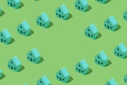 Background pattern of small green model houses arranged in diagonal rows over a matching background with central copy space