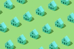 Diagonal rows of little green model houses arranged as a repeat pattern on a matching green background