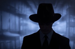 Silhouette of a mysterious man in a vintage style wide brimmed hat in a close up head and shoulders portrait