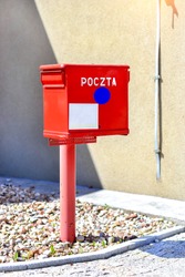 Red metal mailbox of national and international state Polish postal service stands at wall on paving stone. Letter box on main street of Bialystok, Poland