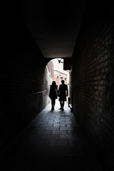 Couple holding hands in dark London alley street grimey