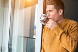 Man in knitted wool sweater drinks tea a cup, relax at home in autumn day. Health care, authenticity, sense of balance and calmness. Fresh air.