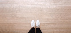 Selfie of feet in fashion sneakers on wooden floor background, top view with copy space, banner style for text