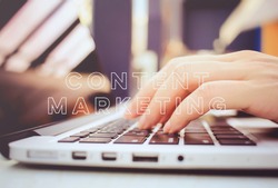 Female hands typing on keyboard of laptop with content marketing word