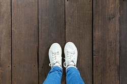 Selfie of feet in fashion sneakers on wooden floor background, top view with copy space