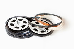 Two 8mm film reels with film strips scattered around. Studio shot. Close-up image isolated on white background.