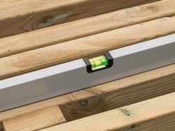 Spirit level checking the level of a plank of wood. Close up image.