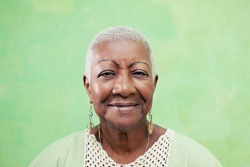 Old black woman portrait, lady in elegant clothes smiling on green background. Copy space