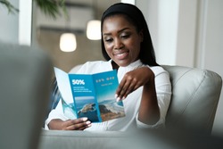 Black Woman Reading Travel Flyer For Holiday Trip