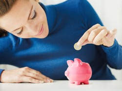 woman putting 1 euro in small piggy bank. Selective focus, Copy space