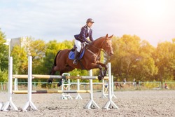 Young rider girl performing jump at horse show jumping competition. Equestrian sport background