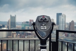 Street binoculars in front of unfocused city. Pittsburgh, Pennsylvania, USA.