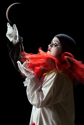 Beautiful Pierrot clown playing mime with the moon