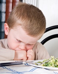 Four year old boy disliking the food on his plate