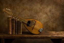 Beautiful old lute and antique books on a rustic old wooden shelf. 