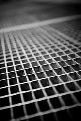 Black and white close up of a sidewalk subway grate with shallow depth of field.