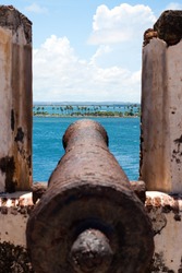 El Morro Fort Cannon covered in rust points out towards the ocean.