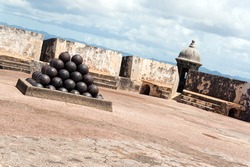 View of the upper interior of El Morro fort located in Old San Juan Puerto Rico.  There is a large pile of cannon balls in a pyramid shape.