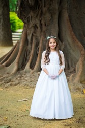 First Communion beautiful girl. Portrait of cute little girl on white dress and wreath on first holy communion 