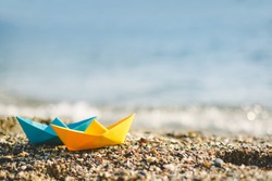 Blue and yellow paper boats on beach outdoors 