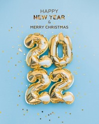 Happy New Year 2022 greeting card. 2022 golden foil balloons numbers and confetti. Top horizontal view copy space new year and christmas holiday concept.