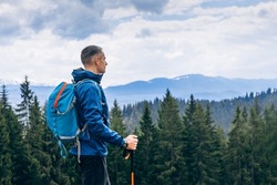Man hiker hiking in mountain forest wearing cold weather accessories, wind jacket and backpack for camping outdoor. Guy portrait lifestyle