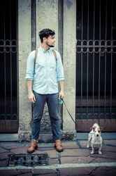 stylish man in the street with a jack russel in front of a wall