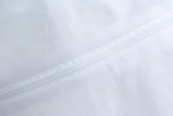 Plastic zipper attached to white nylon fabric. Abstract for background.