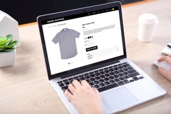 People buying casual shirt on ecommerce website with smart phone on wooden desk