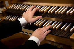 Close up view of a organist hands playing a pipe organ
