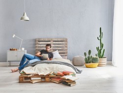 Man is working in the modern bed room. Wooden pallet bed and working from home style. home office decoration.