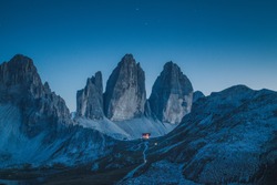 Beautiful view of famous Tre Cime di Lavaredo mountains in the Dolomites mountain range with famous Rifugio Antonio Locatelli alpine hut on a clear starry night in summer, South Tyrol, Italy