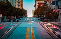 Low angle twilight view of an empty road with cable car tracks leading up a steep hill at famous California Street at dawn, San Francisco, California, USA