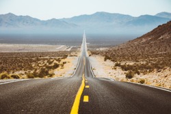 Classic panorama view of an endless straight road running through the barren scenery of the American Southwest with extreme heat haze on a beautiful sunny day with blue sky in summer