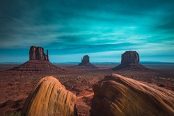Classic panoramic view of scenic Monument Valley with the famous Mittens and Merrick Butte illuminated in beautiful mystic moonlight on a starry night in summer, Arizona, American Southwest, USA