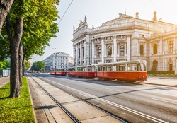 Famous Wiener Ringstrasse with historic Burgtheater (Imperial Court Theatre) and traditional red electric tram at sunrise with retro vintage Instagram style filter effect in Vienna, Austria