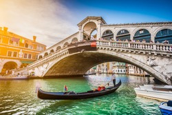 Beautiful view of traditional Gondola on famous Canal Grande with Rialto Bridge at sunset in Venice, Italy with retro vintage Instagram style filter and lens flare effect